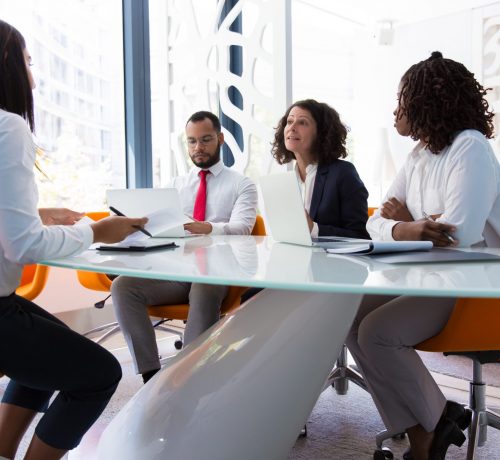 Business leader interviewing job candidate. Business man and women sitting at conference table, using laptops and talking. Discussion agreement concept